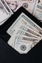 Top view of cash dollar bills in opened black envelope placed on stack of United states cash money as concept of personal budget