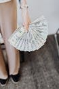 A person holds fanned US dollar bills, symbolizing wealth and finance.
