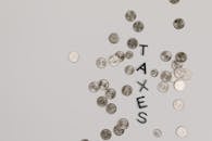 Scattered coins forming the word 'TAXES' on a white surface, symbolizing financial concepts.